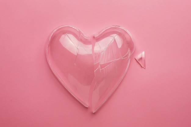 Top view broken glass heart on pink background