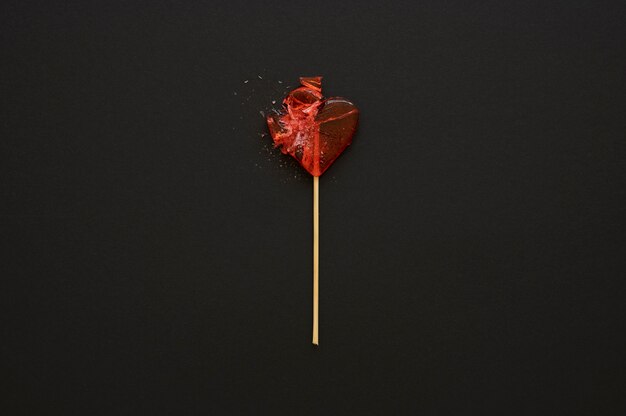 Вид сверху на конфеты с разбитым сердцем на палочке