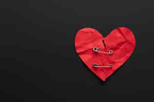 Free photo top view broken red heart with safety pins