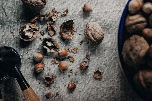 Top view of broken walnuts with hazelnuts and a crusher on a fabric surface