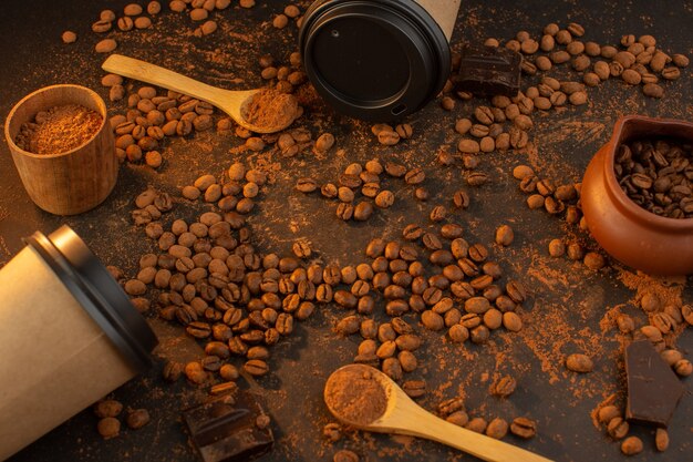 A top view brown coffee seeds with choco bars and coffee cups