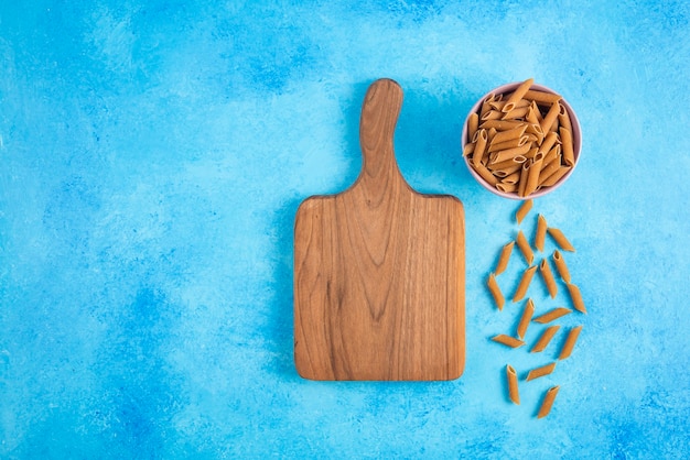 Free photo top view of brown dietic past a and wooden chopping board on blue background.