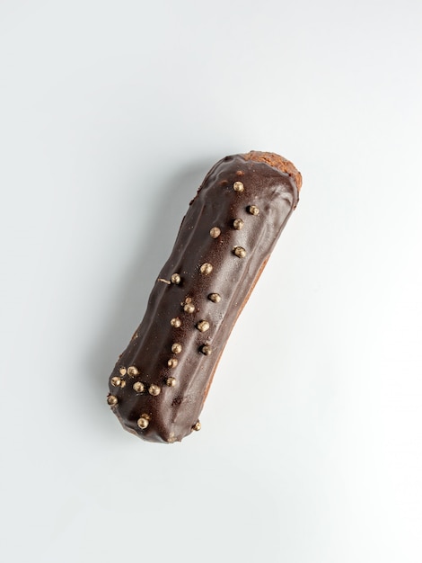 Top view of brown eclair garnished with chocolate and golden beads