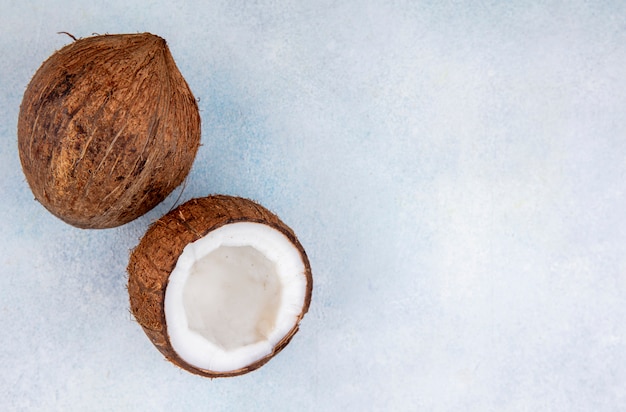 Вид сверху коричневых и свежих кокосов на белом с копией пространства