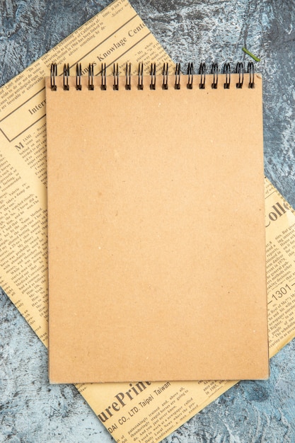 Free photo top view of brown notebook on newspaper on gray background