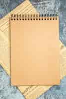 Free photo top view of brown notebook on newspaper on gray background