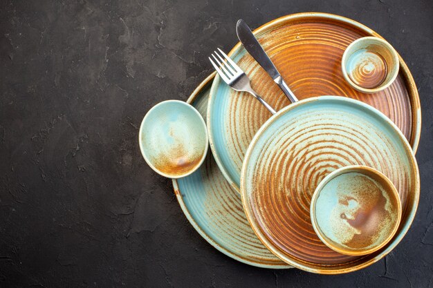 Top view brown plates with fork and knife on dark surface