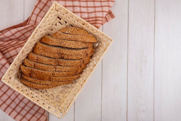 Top view of brown sliced seeded cob in basket on plaid cloth on wooden background with copy space