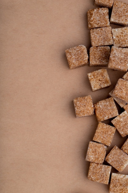 Free photo top view of brown sugar cubes arranged on brown paper texture background with copy space