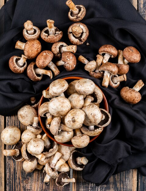 Top view brown and white mushrooms in bowl on black cloth