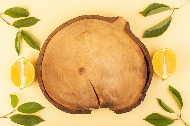 A top view brown wooden desk rustic along with green leaves and sliced lemons apricot colored