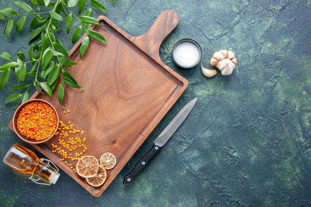 Top view brown wooden desk with orange lentils on dark blue background ancient cuisine color meat butcher kitchen knife food