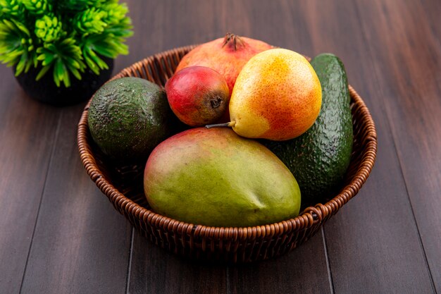 Top view of a bucket of fresh fruits such as pear pomegranate mango on wood