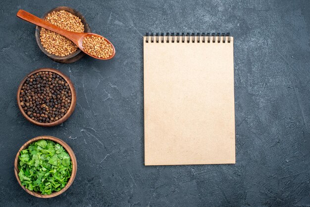 Top view buckwheat and greens with pepper on a dark space