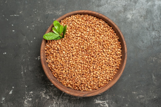 Free photo top view of buckwheat groats with green in a brown bowl on gray background