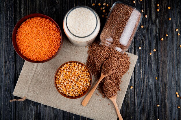 Top view buckwheat is scattered from a can with corn lentils and rice on burlap