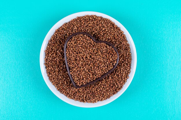 Top view buckwheats in heart shaped bowl inside of another bowl . horizontal