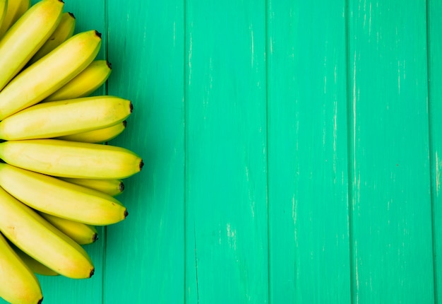 Top view of bunch of bananas isolated on green wood with copy space