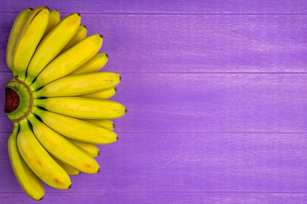 Vista dall'alto del mazzo di banane isolato su legno viola con spazio di copia