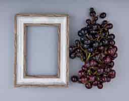 Free photo top view of bunch of black grape and frame on gray background with copy space