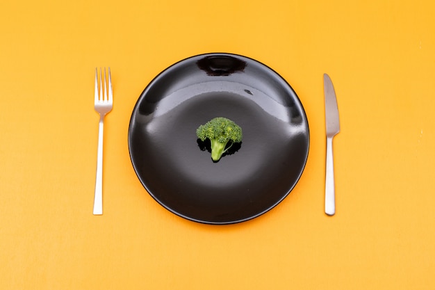 Top view bunch of broccoli in black plate on yellow surface