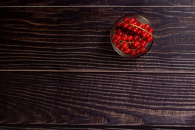 Free photo top view of a bunch of cherry tomatoes in a glass bowl on a wooden table