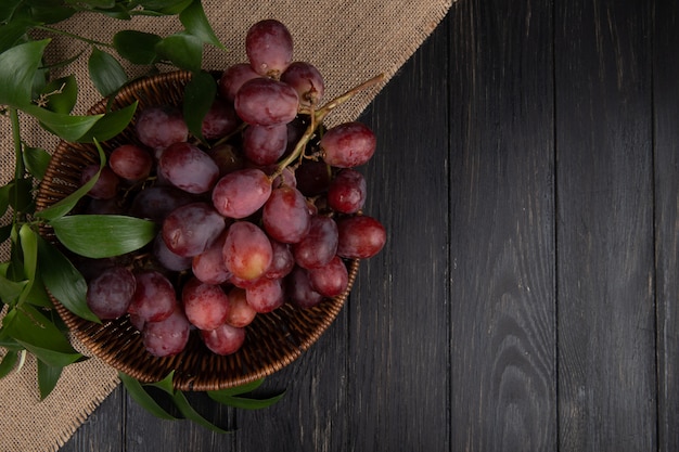 Top view of a bunch of fresh sweet grapes in a wicker basket on wooden table with copy space