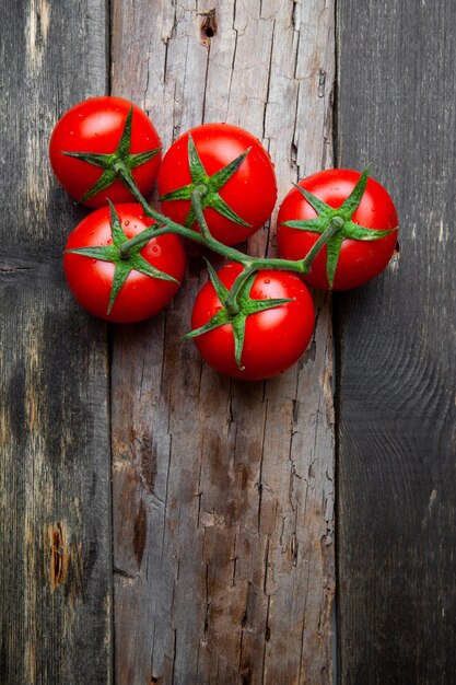 Top view a bunch of tomatoes on old wooden background. vertical