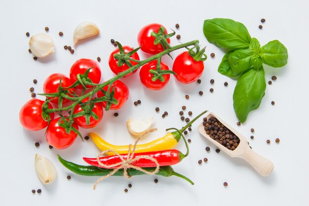 Top view bunch of tomatoes with black pepper, leaves, garlic, chili peppers on gray background. horizontal