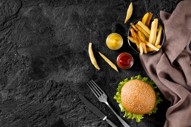 Бесплатное фото Гамбургер и картофель-фри с соусами и копировальным пространством, вид сверху