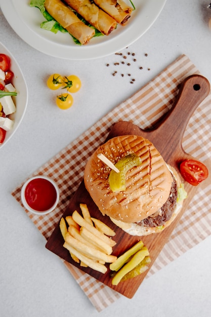 Top view of burger with french fries on a wooden board