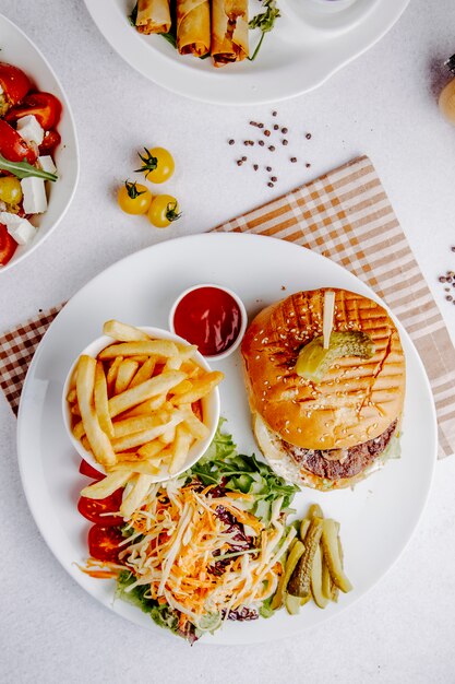 Top view of burger with vegetable salad and french fries