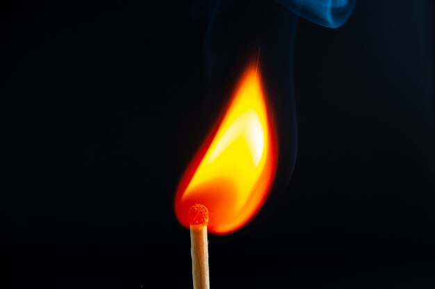 Top view of burning one match lighting ton dark background