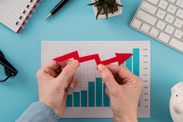 Free photo top view of business items with growth chart and hands holding arrow