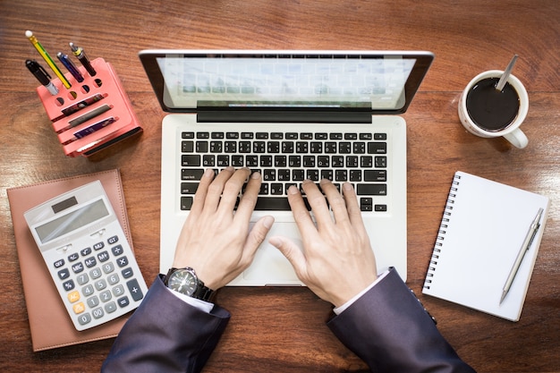 Free photo top view of business man hands working on laptop or tablet pc on wooden desk.