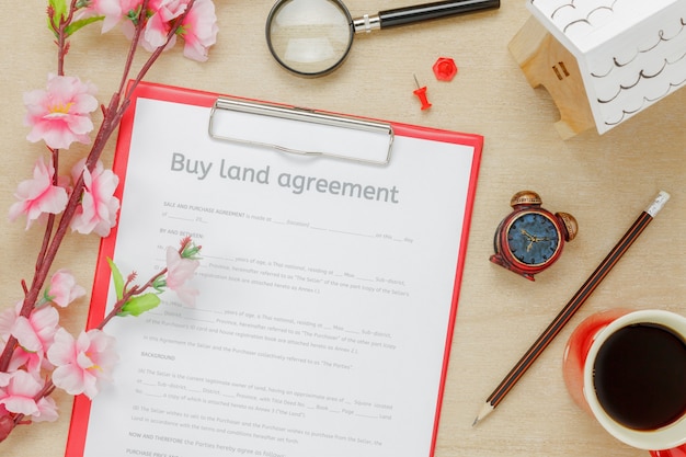 Top view business office desk background.The business buy land ageement form pencil wood house beautiful pink flower on wooden table background with copy space.