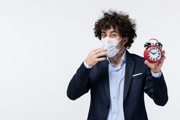 Top view of business person in suit and wearing his mask holding clock in deep thoughts