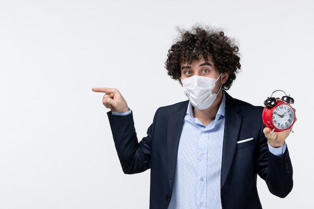 Top view of business person in suit and wearing his mask holding clock pointing something on the right side