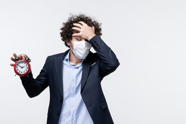 Top view of business person in suit and wearing his mask holding clock suffering from headache