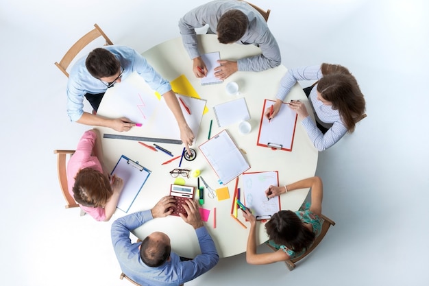白い背景の上の丸いテーブルに座って、事業チームの平面図です。チームワークの成功のコンセプト