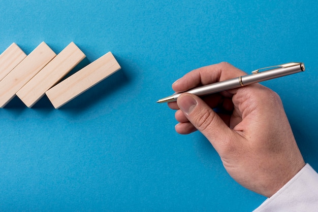 Top view of businessman holding pen with domino pieces