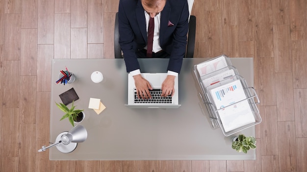 Vista dall'alto della strategia di gestione della digitazione dell'uomo d'affari sul laptop che analizza il profitto dell'azienda