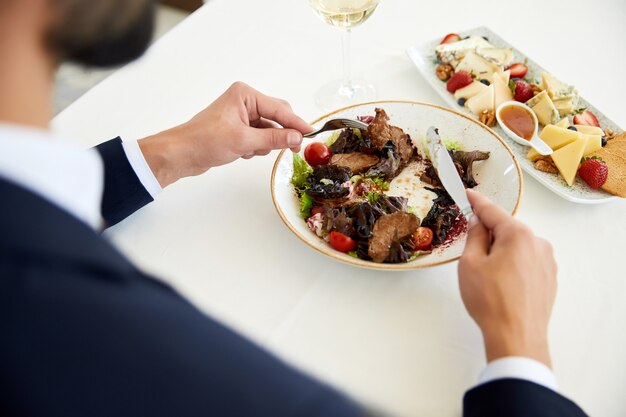 Top view of a businessman who is eating a beef salad at the business lunch