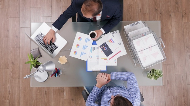 Top view of businessmen discussing company strategy analyzing marketing paperwork