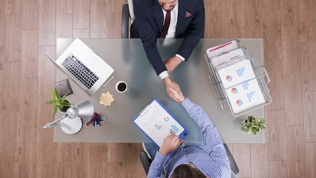Вид сверху бизнесменов, пожимающих руки во время деловых переговоров в офисе запуска
