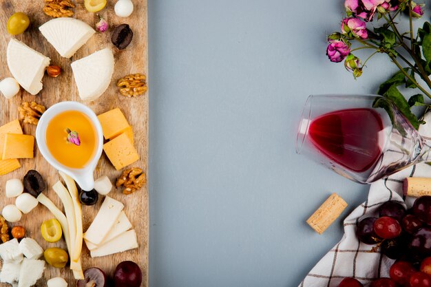 まな板の上にチーズグレープオリーブナッツとバターの上から見るとコピースペースと白でワインのコルクの花のグラス