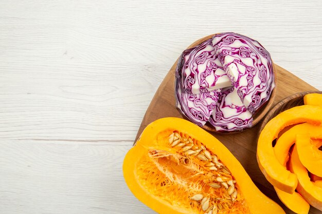 Top view butternut squash cut in half red cabbage and squash slices in bowls on wood board on white background