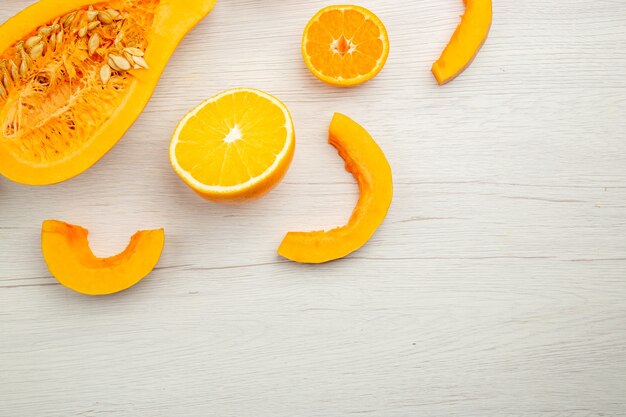 Top view butternut squash slices half persimmon half orange and mandarin on white wooden background