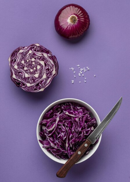 Top view of cabbage in bowl with onion and knife