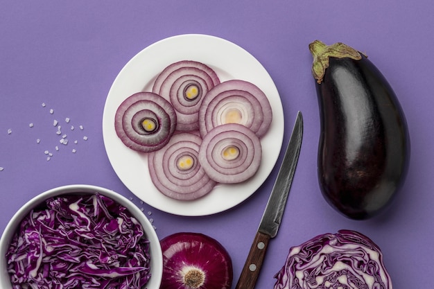 Top view of cabbage in bowl with onion on plate and eggplant